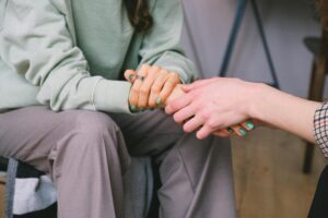 Close-up of two people holding hands during a comforting therapy session.